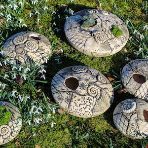 Könnte beinhalten: Ein Set aus drei Keramikbechern mit gesprenkelter, matter Oberfläche. Die Becher sind in den Farbtönen Creme, Hellgrau und Dunkelgrau gehalten. Jeder Becher hat ein schlichtes, modernes Design und einen abgerundeten Henkel. Die Becher sind aufeinander gestapelt.
