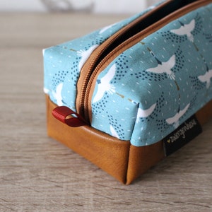 May include: A blue and brown zippered pencil case with a white crane pattern and the text "sweetpepperhouse".