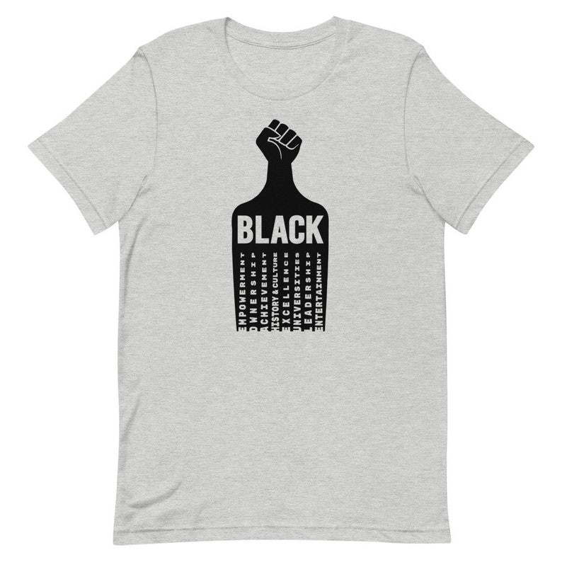 K&ouml;nnte beinhalten: Ein graues T-Shirt mit einer schwarzen Faust, die in die Luft gehoben wird. Das Wort "BLACK" ist in schwarzen Buchstaben unter der Faust geschrieben. Die W&ouml;rter "EMPOWERMENT", "OWNERSHIP", "ACHIEVEMENT", "HISTORY & CULTURE", "UNIVERSITIES", "EXCELLENCE", "LEADERS", "ENTERTAINMENT" sind in einer Spalte unter dem Wort "BLACK" geschrieben.