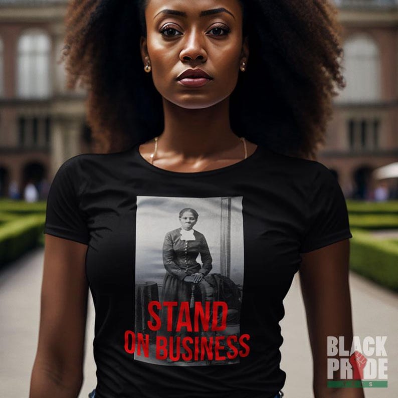 May include: A black t-shirt with a photo of a woman in a white dress and the text "STAND ON BUSINESS" in red.