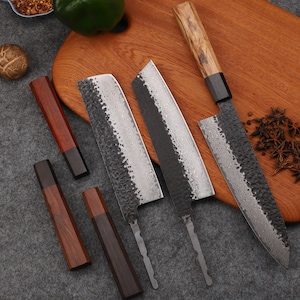 Peut inclure: Trois couteaux de cuisine avec des manches en bois et des lames noires et argentées. Les couteaux sont sur une planche à découper en bois avec quelques étoiles d'anis éparpillées sur la planche.