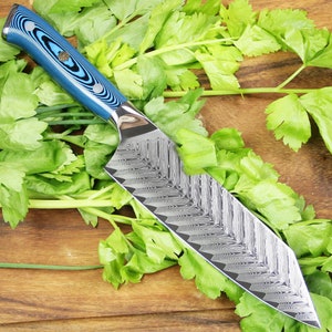 May include: A blue and black handled kitchen knife with a Damascus steel blade. The knife is lying on a wooden cutting board with green parsley.