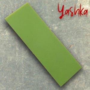 Może przedstawiać: Prostokątny, oliwkowozielony obiekt o teksturowanej powierzchni. Słowo "Yashka" jest napisane czerwoną czcionką w prawym górnym rogu. Obiekt jest ustawiony pod kątem na szarej powierzchni.