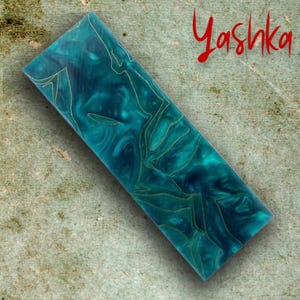 Peut inclure: Pièce rectangulaire en résine turquoise avec des veines dorées et le mot "Yashka" en script rouge. La résine a un aspect marbré avec des tourbillons de turquoise foncée et claire. Les veines dorées créent un motif décoratif.