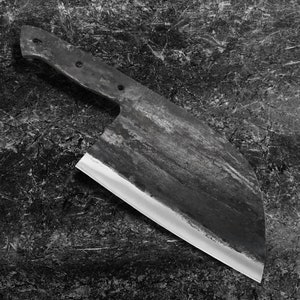 May include: A large, black, metal cleaver with a sharp, silver blade. The cleaver has a worn, rustic appearance.
