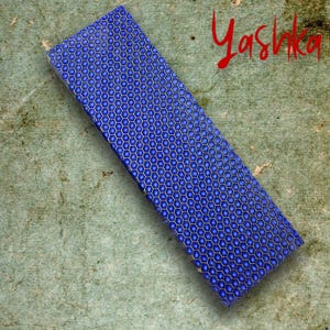 Może przedstawiać: Prostokątny niebieski przedmiot z wzorem plastra miodu. Obiekt ma głęboki niebieski kolor z jaśniejszym niebieskim wzorem. Słowo "Yashka" jest napisane czerwoną kursywą w prawym górnym rogu.