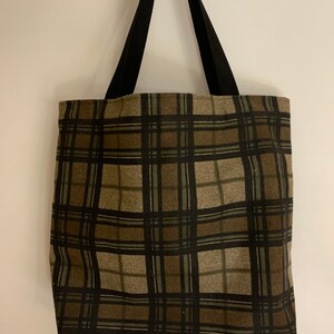 May include: A brown and black plaid tote bag with black straps.
