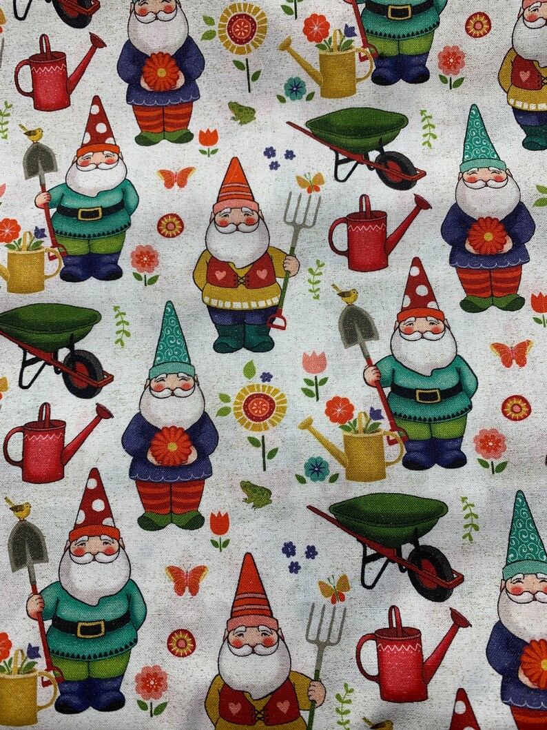 Puede incluir: Una tela blanca con un patr&oacute;n repetido de gnomos, flores, mariposas, carretillas, palas y regaderas. Los gnomos llevan sombreros y ropa de diferentes colores. Las flores son rojas, amarillas y rosas. Las mariposas son naranjas y blancas. Las carretillas son verdes. Las palas son marrones. Las regaderas son rojas y amarillas.