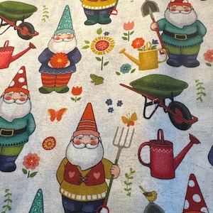 May include: A light gray fabric featuring a repeating pattern of garden gnomes with white beards, colorful hats, and vests. The design includes gardening tools like shovels, pitchforks, red watering cans, green wheelbarrows, flowers, and butterflies.