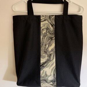 May include: Black tote bag with a vertical stripe of marbled fabric in shades of gray and white.