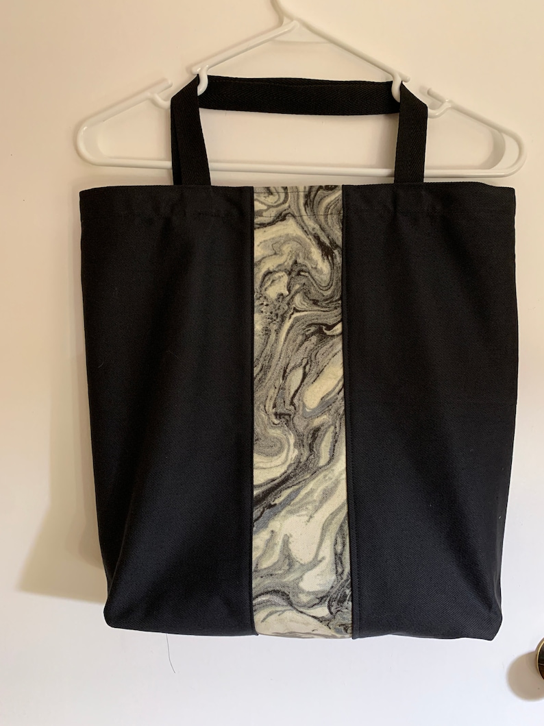 May include: Black tote bag with a vertical stripe of marbled fabric in shades of gray and white.