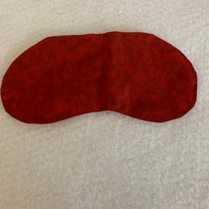 May include: A red sleep mask made of soft fabric. The mask is designed to block out light and help you sleep.
