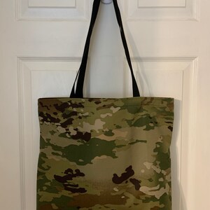 May include: A camouflage tote bag with black straps. The bag is made of a durable fabric and has a spacious interior.