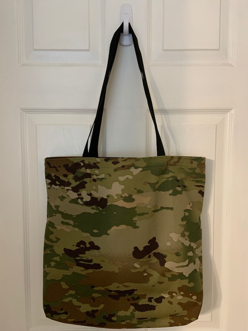 May include: A camouflage tote bag with black straps. The bag is made of a durable fabric and has a spacious interior.