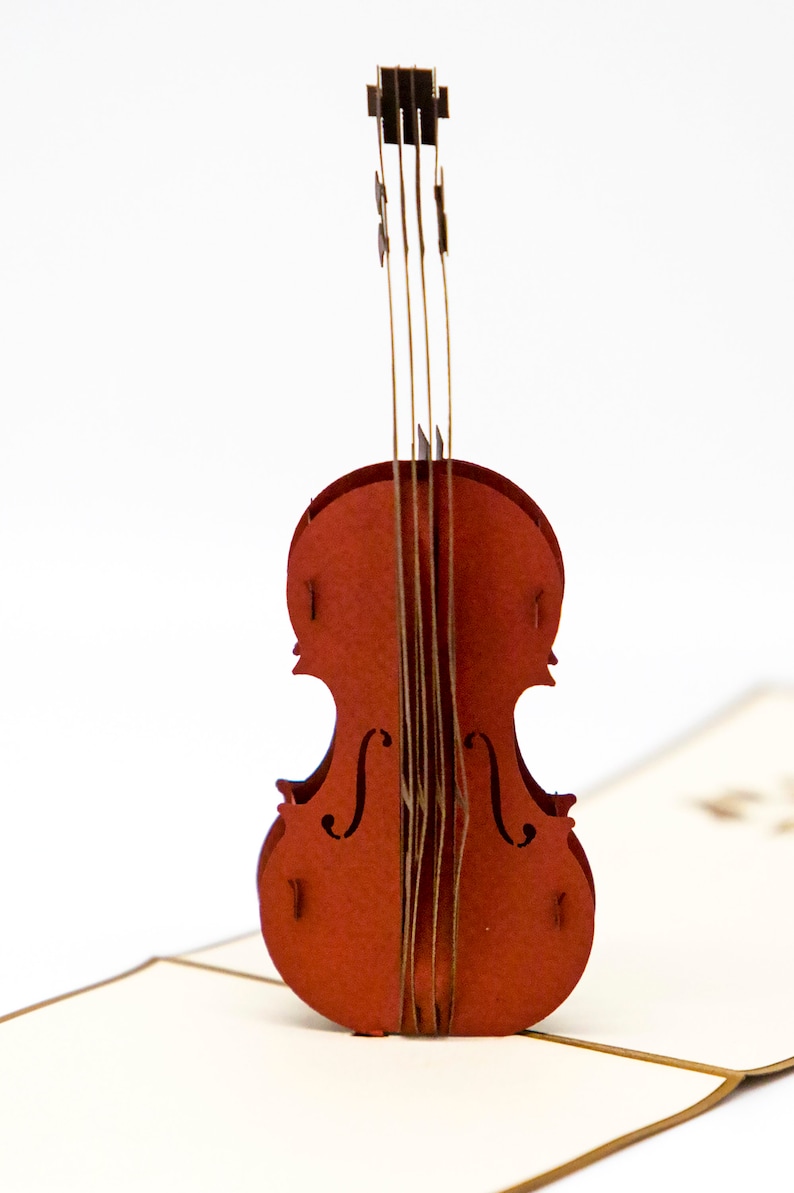 May include: A red papercraft pop-up card featuring a detailed violin. The violin is made of layered paper and has a realistic design.