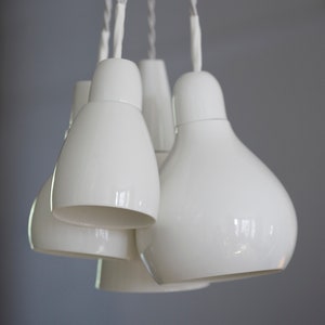 May include: A set of five white ceramic pendant lights hanging from white cords. The lights are shaped like upside-down teardrops.