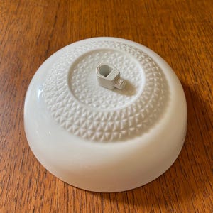 Può includere: Plafoniera in ceramica bianca con un motivo decorativo e un gancio in plastica bianca.