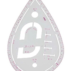 May include: A clear, teardrop-shaped sewing ruler made of plastic, featuring printed red measurement markings along its curved edges. The tool includes various cut-out shapes, including a large central opening and smaller circular holes.