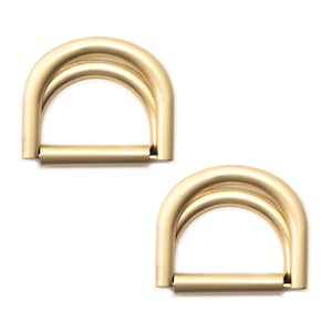May include: Two gold-toned metal D-rings, each with a double loop design. The rings are ideal for attaching to straps, bags, or other accessories.