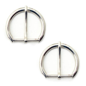 May include: Two silver-toned metal D-ring buckles. The buckles are smooth and have a polished finish.