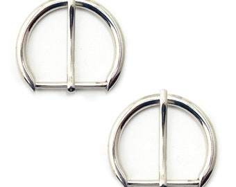 May include: Two silver-toned metal D-ring buckles. The buckles are smooth and have a polished finish.