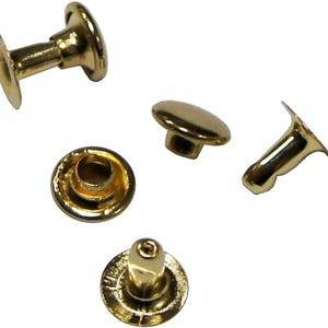 Op de afbeelding: Een verzameling goudkleurige klinknagels, weergegeven tegen een witte achtergrond. De klinknagels hebben een afgeronde kop en een pen voor het bevestigen van materialen. De afbeelding toont de klinknagels vanuit verschillende hoeken, waarbij hun ontwerp en afwerking worden benadrukt.