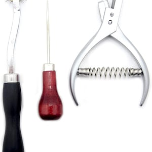 Può includere: Un set di tre strumenti per la lavorazione del cuoio. Gli strumenti includono un punteruolo per cucire con manico in legno, una ruota per cucire con manico in metallo e un punzone per cucire a molla.