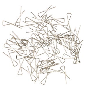 May include: A collection of numerous silver-coloured metal drapery hooks, each featuring a triangular top section and a straight, pointed pin extending from the base. These metallic fasteners are scattered in a random, overlapping arrangement.