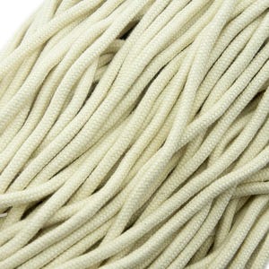 May include: Close-up of a pile of off-white cotton rope. The rope is thick and tightly woven, with a slightly textured surface. The strands are intertwined, creating a dense, tangled mass. The color is a soft, natural cream.