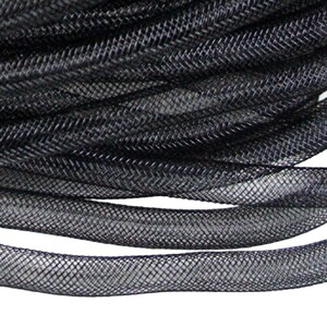 May include: Close-up of a coil of black mesh tubing. The tubing has a woven, net-like texture, and the material appears to be flexible. The mesh is tightly woven, creating a solid black appearance. The image is well-lit, highlighting the texture of the material.