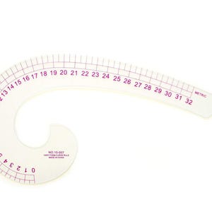Può includere: Un righello curvo francese in plastica trasparente con segni e numeri stampati in viola da 0 a 32 centimetri. Lo strumento riporta la scritta NO.10-007 VARY FORM CURVE RULE MADE IN CHINA e include una scala metrica per le misurazioni.