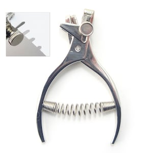 May include: A silver metal tool with a spring and a knob. The tool is used for punching holes in leather.