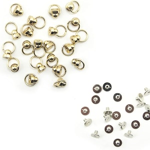 Peut inclure: Un ensemble de bagues en métal doré avec une petite boule sur le dessus, et un ensemble de fixations à vis en métal argenté.