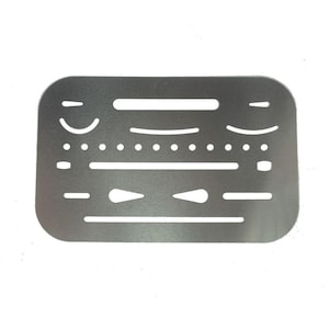 May include: A silver-colored metal template with various cut-out shapes, including curved lines, dots, and elongated slots. The rectangular template has rounded corners and is designed for drawing and design purposes.