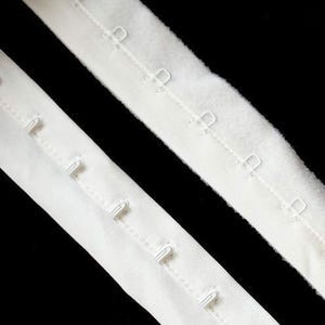 May include: Two white bra strap extenders with metal hooks. The extenders are made of a soft, stretchy fabric.