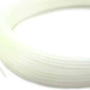 May include: A close-up of a spool of white string. The string is tightly wound and appears to be made of a synthetic material.