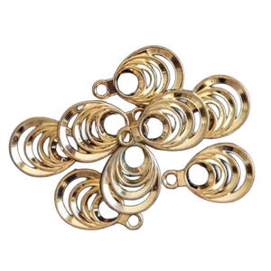 May include: A collection of gold-toned metal charms, each featuring a series of concentric, teardrop-shaped cutouts. Every charm includes a small circular loop at the top for attachment, with a polished, reflective surface finish throughout.