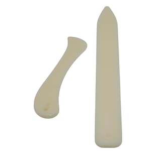 May include: Two off-white bone folders for paper crafting. One tool is long, straight, and pointed at one end, while the other is shorter, curved, and features a small circular hole at the rounded base. Both tools have smooth, solid surfaces.