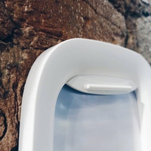 K&ouml;nnte beinhalten: Eine wei&szlig;e Plastik-Haustierklappe mit einem wei&szlig;en Plastikrahmen. Die Klappe ist geschlossen und der Rahmen ist an einer braunen Backsteinwand montiert.
