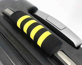 May include: Black suitcase handle with a yellow and black striped handle cover.