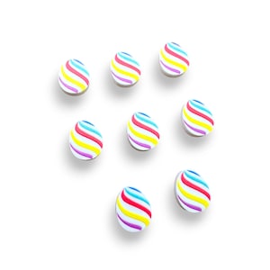 May include: Eight white round buttons with colorful stripes. The stripes are red, yellow, blue, and pink.
