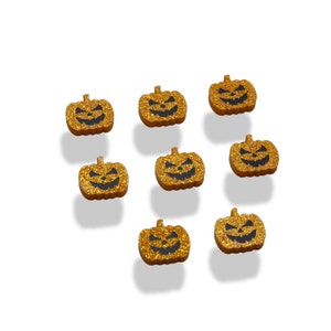 May include: Eight gold glitter pumpkin shaped ornaments with black jack-o'-lantern faces.
