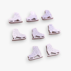 May include: Eight small, flat, die-cut ice skate shapes arranged in a cluster. Each skate features a silver glitter finish on the upper portion and a brown base, showcasing the blade and boot structure in a simple, uniform, and decorative design.