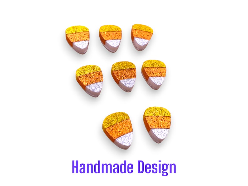 May include: Seven triangular candy corn shaped pieces arranged in three rows. Each piece features three horizontal bands of glittery texture in yellow, orange, and white. The text "Handmade Design" is printed in purple at the bottom of the image.