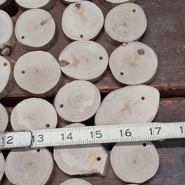 One dozen de-barked river birch rounds, 1-1/2" -2" dia x 3/8" thick, sanded and are drilled 1/8" for hanging