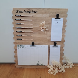 Könnte beinhalten: Ein Holz-Wandorganizer mit einem Speiseplan, einem Wochenplaner, einer Einkaufsliste und einer To-Do-Liste. Der Organizer hat eine helle Holzoptik und ist mit Trockenblumen und Grünpflanzen dekoriert.