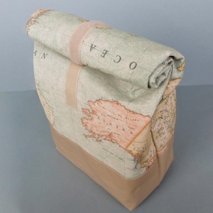 Könnte beinhalten: Eine braune und beige Canvas-Tragetasche mit einem Karten-Druck. Die Tasche hat einen gerollten oberen Rand mit einem braunen Riemen und dem Wort "OCEA" darauf gedruckt. Die Tasche ist aus robustem Canvas-Material gefertigt und hat einen braunen Lederboden.