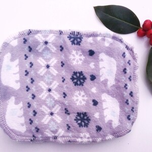 May include: A purple fabric reusable makeup remover pad with a white polar bear and snowflake pattern.