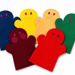 Könnte beinhalten: Eine Sammlung farbenfroher Handpuppen aus Filz in verschiedenen Farben, darunter Blau, Gelb, Orange, Grün, Rot und Weinrot. Jede Puppe hat gestickte Gesichtsausdrücke, die verschiedene Emotionen wie Freude, Trauer und Überraschung zeigen.
