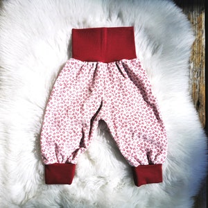 Op de afbeelding: Rode en witte babybroek met een rode elastische tailleband.